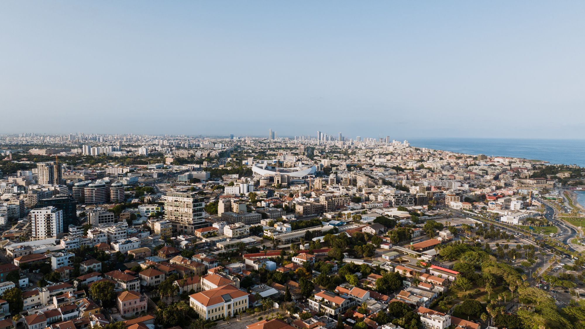 Wide aerial view of Tel Aviv's dense cityscape and Mediterranean coast